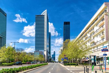 Varşova, Polonya - 20 Nisan 2025: Modern gökdelenlerin yüksek demir ve cam binaları ve Varşova şehir merkezindeki caddede trafik. Avrupa 'da ofis inşaatı ve şirket işleri