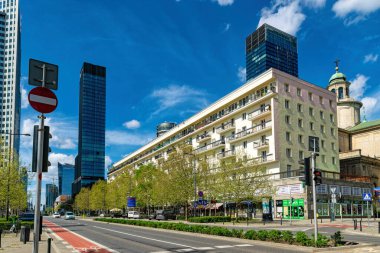 Varşova, Polonya - 20 Nisan 2025: Modern gökdelenlerin yüksek demir ve cam binaları ve Varşova şehir merkezindeki caddede trafik. Avrupa 'da ofis inşaatı ve şirket işleri