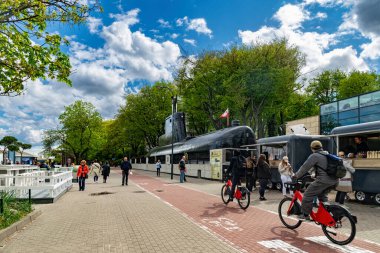 Gdynia, Polonya - 04 Mayıs 2025: Gdynia deniz kenarı bulvarı. Tarihi denizaltı Sokol (Falcon) ve yürüyen turistler. Polonya 'da bahar tatili