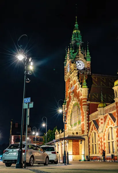 Gdansk, Polonya - 07 Ekim 2024: Gdansk 'taki tren istasyonunun tarihi tuğlaları ve bir saat kulesi. Gece kenti sokağı