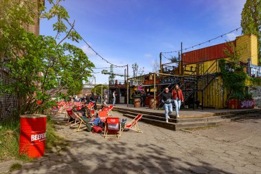 Gdansk, Polonya - 10 Mayıs 2025: Gdansk 'taki tarihi tersanenin ünlü turizm ve eğlence alanı. Yıkılan endüstri binaları, vinçler ve gıda alanlarından yiyecek alan insanlar.