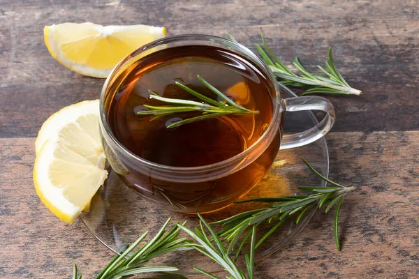 stock image Rosemary tea with lemon slices on wooden background