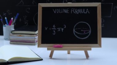 Blackboard with hand written geometry volume formulas and geometric shapes and figures