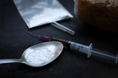 Heroin liquid and heroin powder on a black background, concept of a narcotic substance