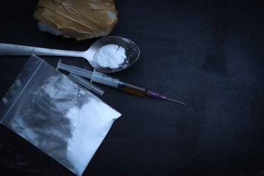 Heroin liquid and heroin powder on a black background, concept of a narcotic substance