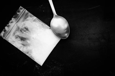 spoon and heroin powder on a black background, concept of a narcotic substance
