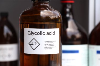 Camdaki glikolik asit, fabrika veya laboratuardaki konteynırlardaki tehlikeli kimyasallar ve semboller. 