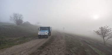 Sisli bir sabahta kırsalda araba sürüyor.