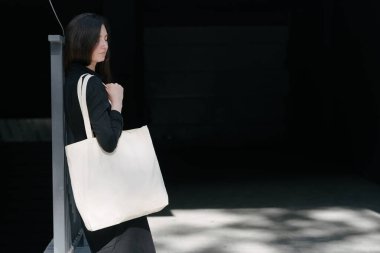 Kentsel şehir arka plan karşı beyaz tekstil eko çanta tutan kadın. Ekoloji veya çevre koruma kavramı. Sahte için beyaz eko çanta.