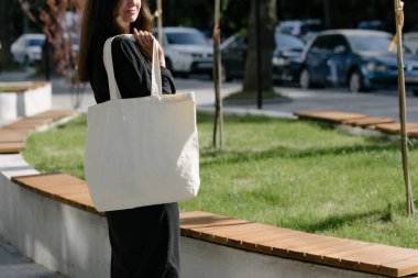 Kentsel şehir arka plan karşı beyaz tekstil eko çanta tutan kadın. Ekoloji veya çevre koruma kavramı. Sahte için beyaz eko çanta.