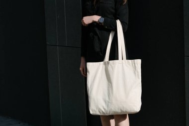 Kentsel şehir arka plan karşı beyaz tekstil eko çanta tutan kadın. Ekoloji veya çevre koruma kavramı. Sahte için beyaz eko çanta.