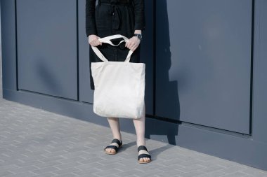 Kentsel şehir arka plan karşı beyaz tekstil eko çanta tutan kadın. Ekoloji veya çevre koruma kavramı. Sahte için beyaz eko çanta.