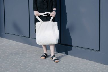 Kentsel şehir arka plan karşı beyaz tekstil eko çanta tutan kadın. Ekoloji veya çevre koruma kavramı. Sahte için beyaz eko çanta.