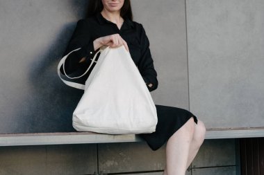 Kentsel şehir arka plan karşı beyaz tekstil eko çanta tutan kadın. Ekoloji veya çevre koruma kavramı. Sahte için beyaz eko çanta.