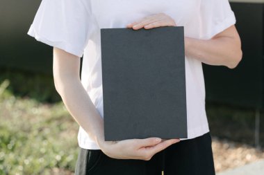 Siyah kitap kapağı bir kadının elinde. Model için kitap kapağı