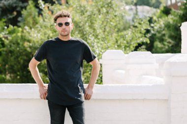 Hippi yakışıklı erkek manken siyah boş tişört giyiyor. Logonuz için yeri var. Ya da şehir tarzı tasarım.