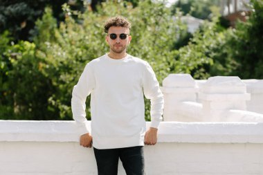 Beyaz sweatshirt ya da kapüşonlu bir adam şehrin sokaklarında boş yeri olan logo tasarımları ya da tasarım baskıları yapıyor..