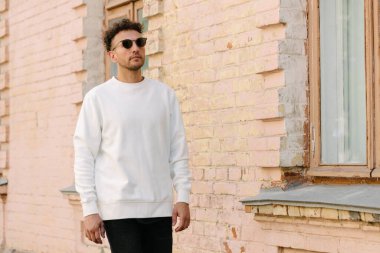 Beyaz sweatshirt ya da kapüşonlu bir adam şehrin sokaklarında boş yeri olan logo tasarımları ya da tasarım baskıları yapıyor..