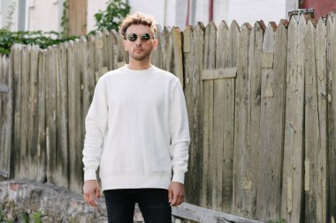 Beyaz sweatshirt ya da kapüşonlu bir adam şehrin sokaklarında boş yeri olan logo tasarımları ya da tasarım baskıları yapıyor..