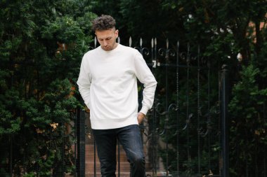 Beyaz sweatshirt ya da kapüşonlu bir adam şehrin sokaklarında boş yeri olan logo tasarımları ya da tasarım baskıları yapıyor..