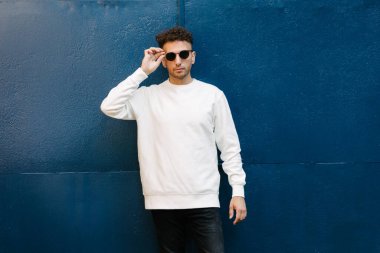 Beyaz sweatshirt ya da kapüşonlu bir adam şehrin sokaklarında boş yeri olan logo tasarımları ya da tasarım baskıları yapıyor..