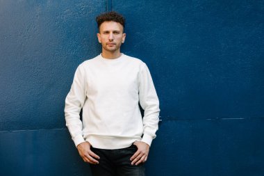 Beyaz sweatshirt ya da kapüşonlu bir adam şehrin sokaklarında boş yeri olan logo tasarımları ya da tasarım baskıları yapıyor..