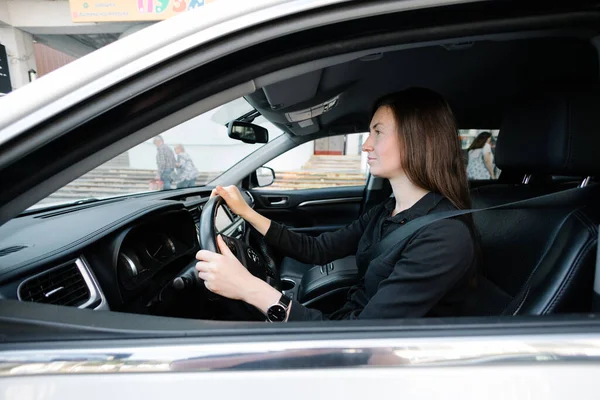 Woman in black clothes driving luxurious car