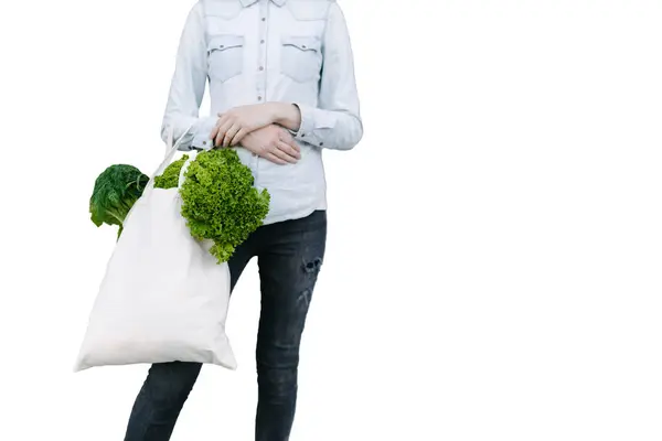 女人拿着一个装满杂货的环保袋 蔬菜和水果挂在袋子里 生态或环境保护概念 白色生态袋模拟 免版税图库照片