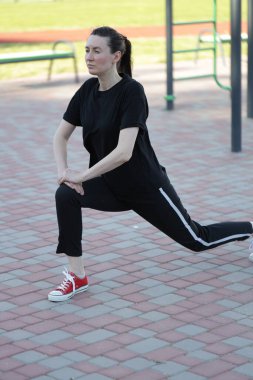 Kadın egzersiz yapıyor ya da dışarıda egzersiz yapıyor.