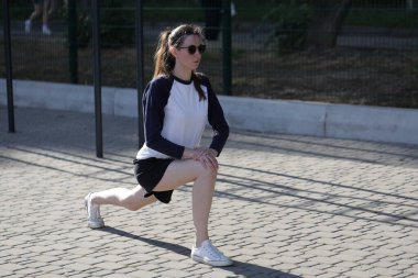 Kadın egzersiz yapıyor ya da dışarıda egzersiz yapıyor.