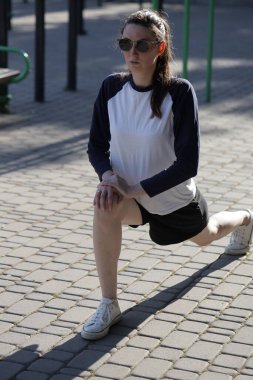 Kadın egzersiz yapıyor ya da dışarıda egzersiz yapıyor.