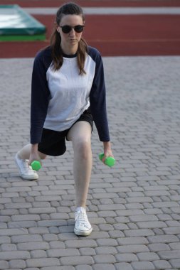 Kadın egzersiz yapıyor ya da dışarıda egzersiz yapıyor.