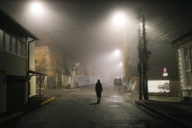 Sisli bir gecede şehirde tek başına yürüyen bir kadın.