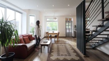 Modern bir özel evin oturma odasında bir kadın.