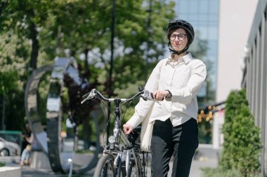 Eko çanta ya da pamuklu çanta taşıyan bir kadın şehirde bisiklet sürerken