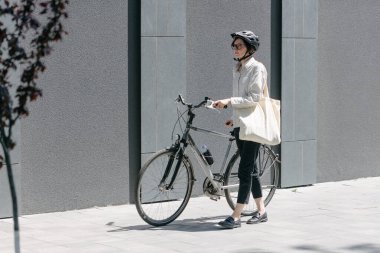 Eko çanta ya da pamuklu çanta taşıyan bir kadın şehirde bisiklet sürerken