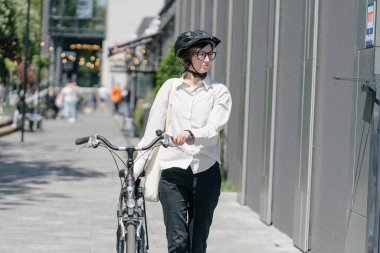 Eko çanta ya da pamuklu çanta taşıyan bir kadın şehirde bisiklet sürerken