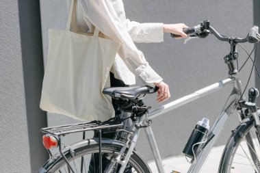 Eko çanta ya da pamuklu çanta taşıyan bir kadın şehirde bisiklet sürerken