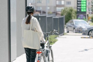 Eko çanta ya da pamuklu çanta taşıyan bir kadın şehirde bisiklet sürerken