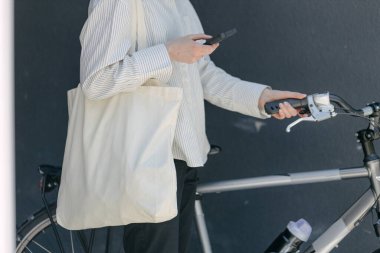 Eko çanta ya da pamuklu çanta taşıyan bir kadın şehirde bisiklet sürerken