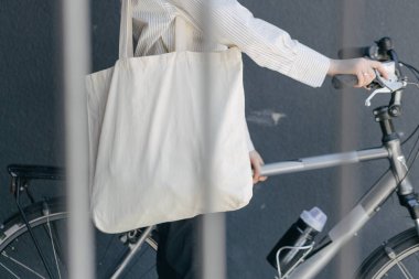 Eko çanta ya da pamuklu çanta taşıyan bir kadın şehirde bisiklet sürerken