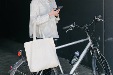 Eko çanta ya da pamuklu çanta taşıyan bir kadın şehirde bisiklet sürerken