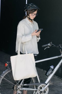 Eko çanta ya da pamuklu çanta taşıyan bir kadın şehirde bisiklet sürerken