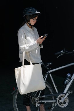 Eko çanta ya da pamuklu çanta taşıyan bir kadın şehirde bisiklet sürerken