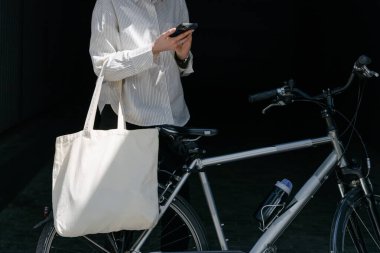 Eko çanta ya da pamuklu çanta taşıyan bir kadın şehirde bisiklet sürerken