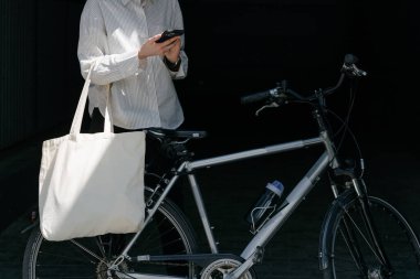 Eko çanta ya da pamuklu çanta taşıyan bir kadın şehirde bisiklet sürerken