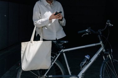 Eko çanta ya da pamuklu çanta taşıyan bir kadın şehirde bisiklet sürerken