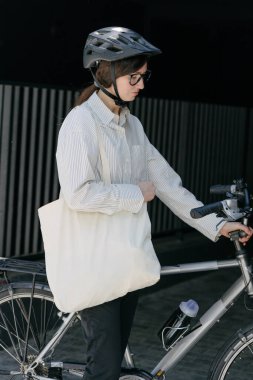 Eko çanta ya da pamuklu çanta taşıyan bir kadın şehirde bisiklet sürerken