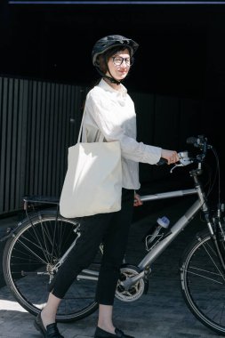 Eko çanta ya da pamuklu çanta taşıyan bir kadın şehirde bisiklet sürerken