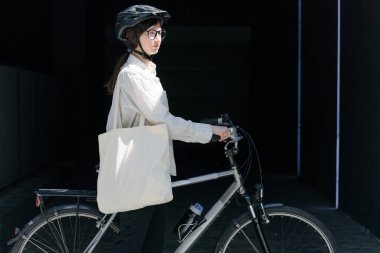 Eko çanta ya da pamuklu çanta taşıyan bir kadın şehirde bisiklet sürerken